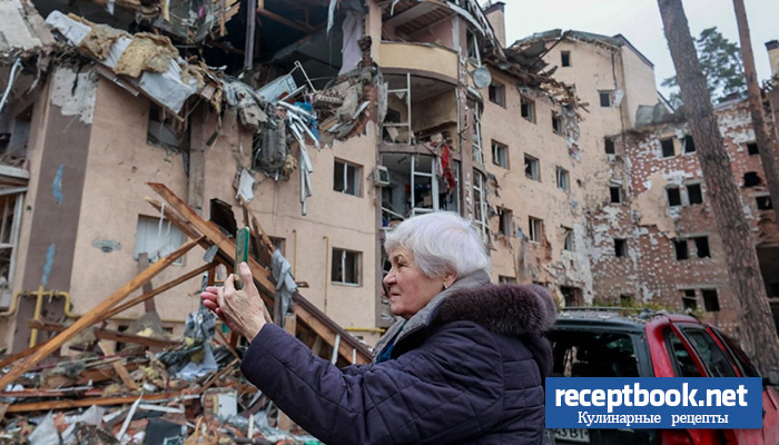 Пожилая женщина фотографирует свой разрушенный дом в Ирпене